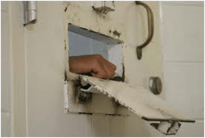 Hand reaching through a prison cell slot