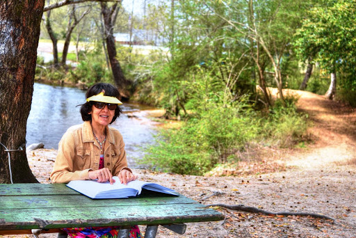 Sue Brasel sitting at picnic table, reading a braille book.